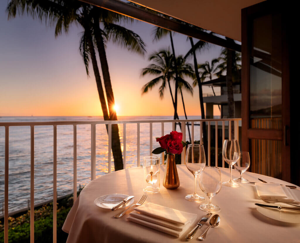 La Mer dining room at Halekulani at sunset, with open windows facing the Pacific and Diamond Head.