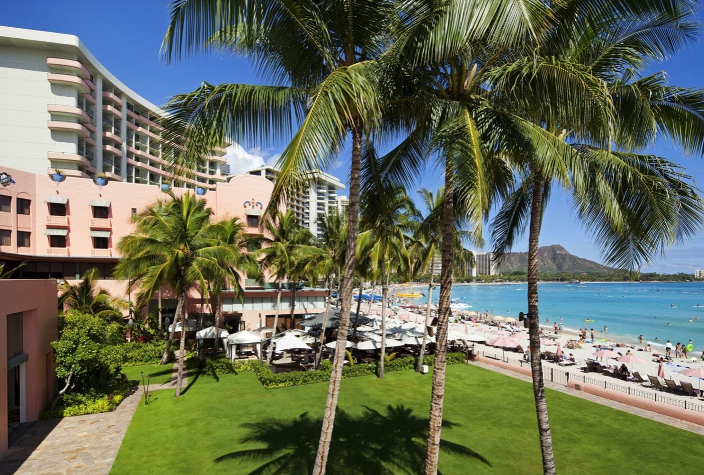The Royal Hawaiian's iconic pink facade with Ocean Lawn and Waikiki Beach.